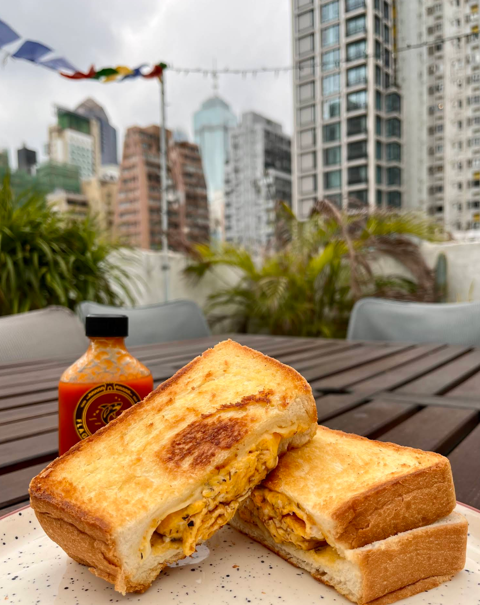 Scrambled egg and cheese toastie on the terrace, with the Sai Wan skyline behind